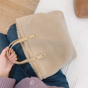 Detail of beige faux shearling tote bag with brown leather handles and gold rivets