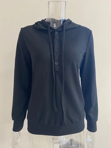 Detalle de la sudadera negra con textura de canalé, botones frontales y cordón ajustable