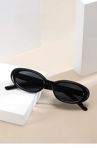 Detail of oval black frame sunglasses displayed on minimalist geometric stone props