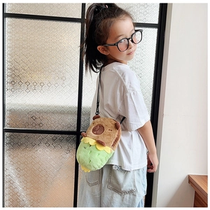 Detail view of a child wearing a brown Capybara plush crossbody bag with green strap