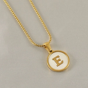 Macro shot of gold box chain and round white pendant with gold letter E engraving