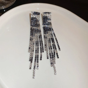 Detail view of silver tassel earrings featuring black and white zircon stone patterns