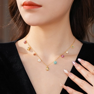 Detail of gold necklace with colorful floral pendants and a ladybug on a model's neck