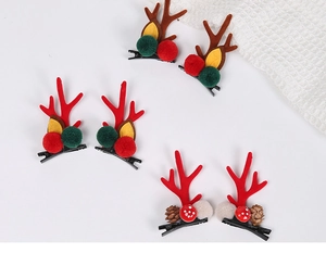 Detailed view of Christmas reindeer antler hair clips with plush pom-poms and pine cones