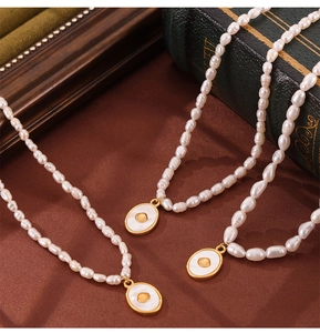 Close-up of baroque pearl necklaces with gold shell pendants on brown velvet background