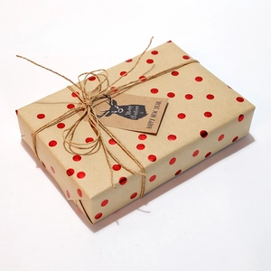Christmas kraft wrapping paper with red metallic dots, twine, and reindeer gift tags