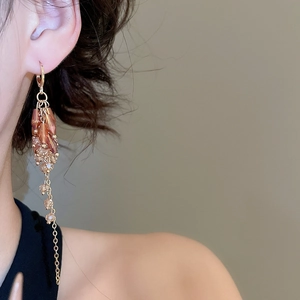 Detail of bohemian long amber crystal fringe earrings with gold chain on model