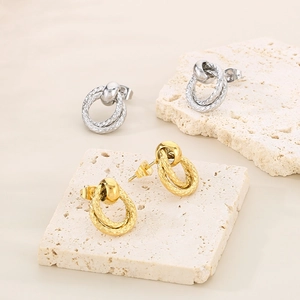 Detail of interlocking gold and silver double-hoop earrings with snake texture pattern