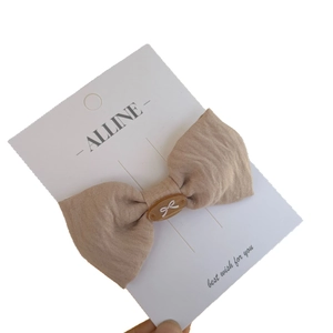 Minimalist beige cotton linen bow hair clip with decorative brown resin button detail