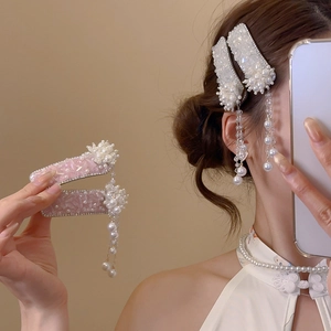 Detail of floral hair clip with rhinestones, pearls and long tassels in elegant style