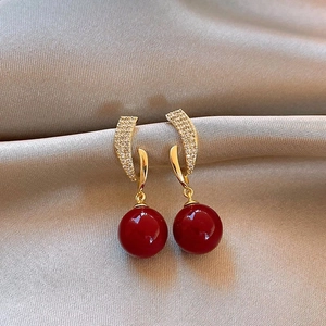 Détail de boucles d'oreilles pendantes rouges avec strass sur tissu en soie grise