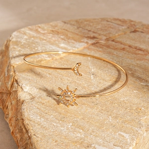 Detailed shot of gold sun and moon cuff bracelet with rhinestones on natural stone base