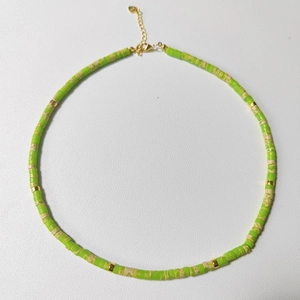 Detail of bohemian natural stone necklace with green beads and gold spacers on white background