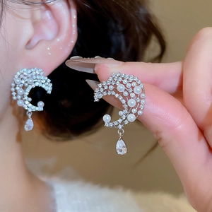 Detail of moon-shaped pearl earrings with zirconia and a teardrop crystal pendant