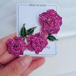 Detail of rose brooch with pink crystals and green leaves on a silver-tone base