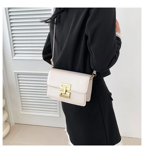White minimalist square crossbody bag with gold lock buckle shown on shoulder of model