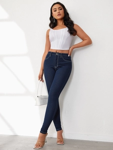 Detail of high waisted dark blue skinny jeans featuring white contrast stitching on denim