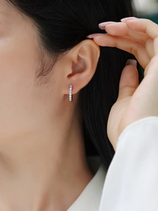 Close-up of sparkling S925 silver hoop earring with cubic zirconia on female model ear