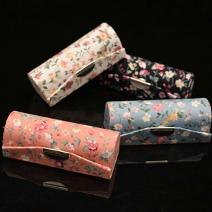 Detail of four floral fabric lipstick boxes with mirrors and silver metal buckles