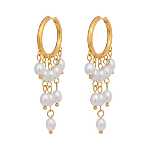 Close-up of golden tassel earrings with white pearls on a minimalist white background