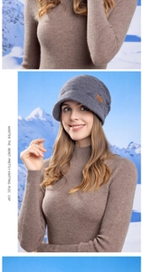 Close-up of thick knit dark grey beanie with a brown leather logo in a snowy setting