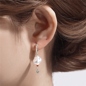 Detail of twisted silver hoop earrings with white baroque pearl and star charm on model
