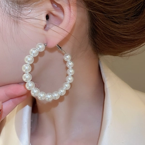Close-up of a silver pearl hoop earring on a model's ear showing elegant design
