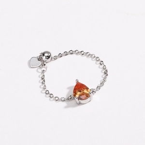 Détail d'une bague chaîne avec pierre orange en poire et pendentif en cœur poli