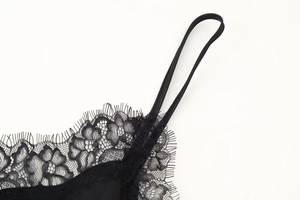 Detailed close-up of delicate black eyelash lace trim and fine strap on the dress