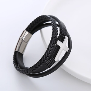 Macro detail of multi-layer braided leather bracelet with silver cross and magnetic clasp