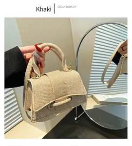 Détail du sac à main tissé kaki avec rabat texturé et fermoir décoratif au soleil