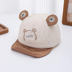 Detalle de gorra de sol para bebé con orejas de oso, tela beige y bordado suave