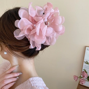 Detail of large light pink lace flower hair claw with pearls on a model's hair bun