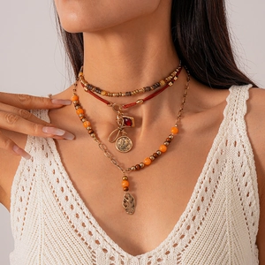 Macro shot of bohemian layered necklace with wood beads and red leaf coin pendants