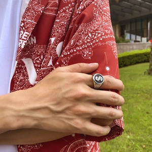Retro silver ring for men with black oval dollar sign motif on hand in outdoor setting