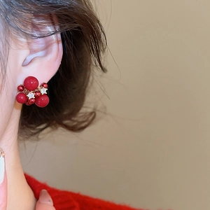 Detail of red beaded firework earrings with zircon crystals worn by a model in warm light