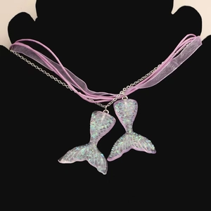 Détail de pendentifs queue de sirène violets à paillettes avec chaîne argentée et ruban