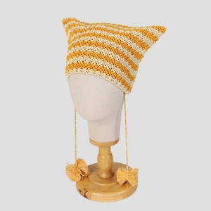 Cute yellow and white striped crochet cat ear beanie with pom-pom tassels on a display stand