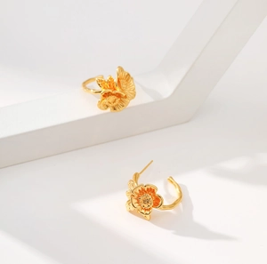 Detailed view of 18K gold floral earrings with delicate texture on a white geometric base