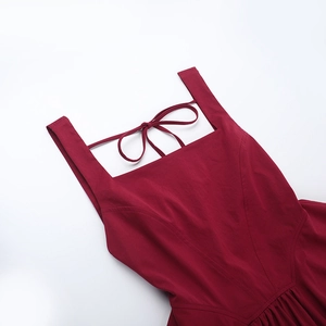 Close-up of wine red sleeveless dress featuring a square neck and tie-back bow detail