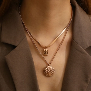 Detail of layered gold titanium necklace with square and round honeycomb pendants on model