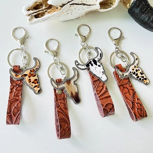 Detail view of western cow head keychains with leopard print and embossed leather straps