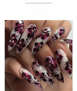 Macro shot of long stiletto press-on nails featuring purple floral patterns and silver studs