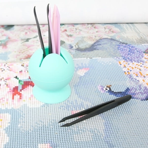 Light green suction cup tool holder with plastic tweezers on a diamond painting canvas