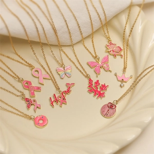 Detailed shot of gold butterfly and donut pendants with pink enamel on chain necklaces