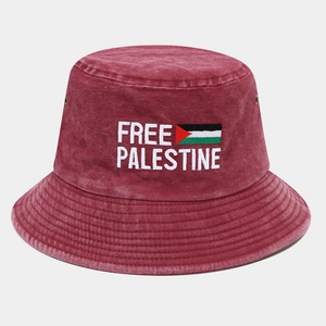Dettaglio del ricamo bianco Free Palestine su un cappello a secchiello in cotone rosso