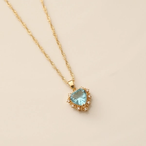Macro view of gold heart necklace with blue gemstone and sparkling zircon stones