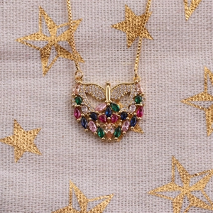 Gold angel heart necklace featuring colorful zircons on a textured beige fabric background