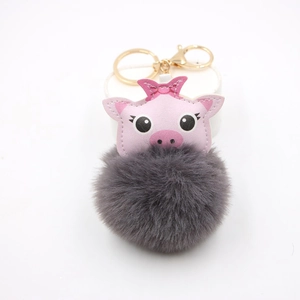 Detail of a pink leather pig head with bow and dark grey plush pompom keychain