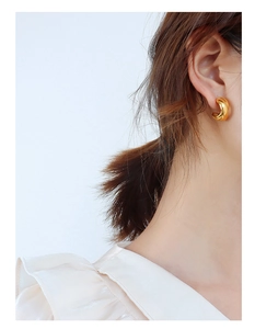Close-up of elegant crossover gold twisted earrings worn on model's ear